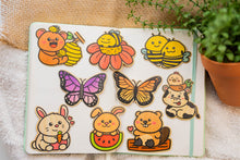 Load image into Gallery viewer, Bamboo Sticker Collection - A captivating array of nine distinct bamboo stickers, each contributing its unique charm and eco-friendly appeal, beautifully arranged on a notebook.
