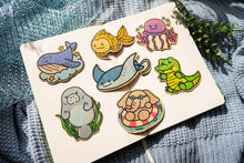 Load image into Gallery viewer, Whale, goldfish, jellyfish, stingray, and crocodile bamboo stickers gracefully displayed on a notebook. Dive into the mesmerizing underwater world with these eco-friendly designs. 🐋🐠🦑 #AquaticBambooStickers #OceanArt #EcoFriendlyDesign
