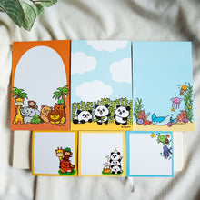 Load image into Gallery viewer, Zoo animals come to life on the large orange memo pad with palm trees, featuring a playful cast including a giraffe, elephant, monkey, turtle, lion, and bear. On the blue and white panda memo pad, adorable pandas play among bamboo sticks in a cloud-filled backdrop. Dive into the ocean with the aquatic-themed memo pad showcasing the ocean floor, complete with a stingray, corals, and jellyfish. Below, find smaller versions of each design in the form of convenient sticky notes
